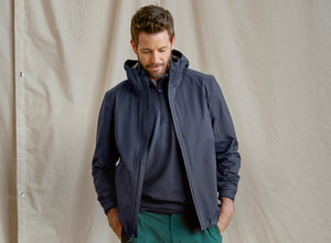 Man wearing a dark blue jacket against a beige background