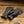 Load image into Gallery viewer, Pair of dark brown leather gloves with knitted cuffs on a wooden surface