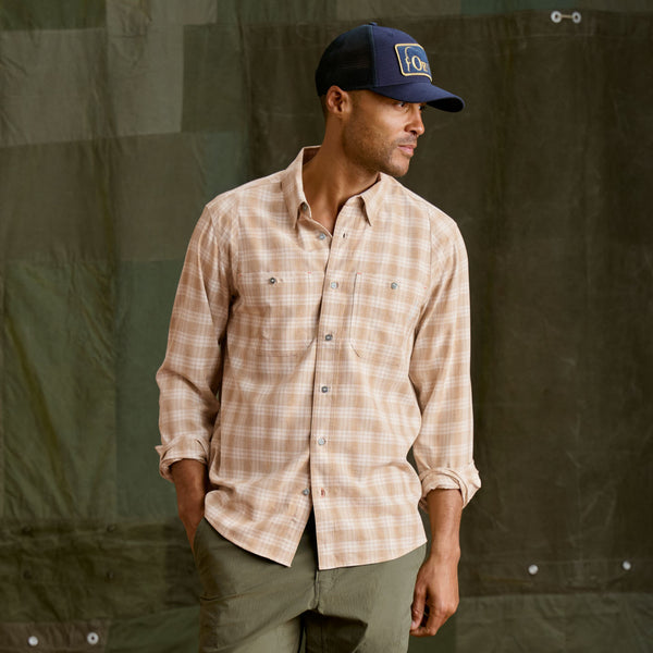 Man wearing dark blue cap, beige shirt and dark green pants.