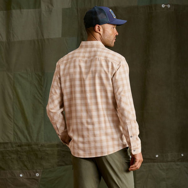 Man modelling a beige and white checkered shirt, dark blue cap and green trousers