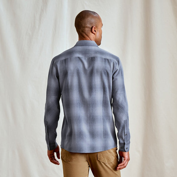 Man wearing a gray plaid shirt against a plain background
