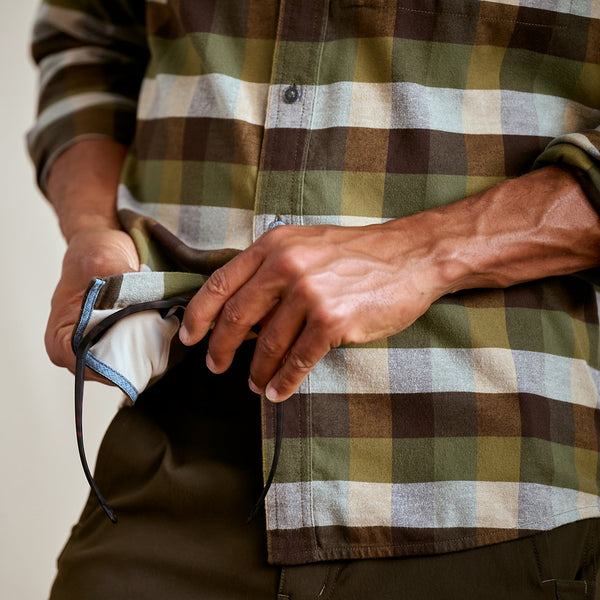 Person wearing a plaid shirt holding a mask with a neutral background