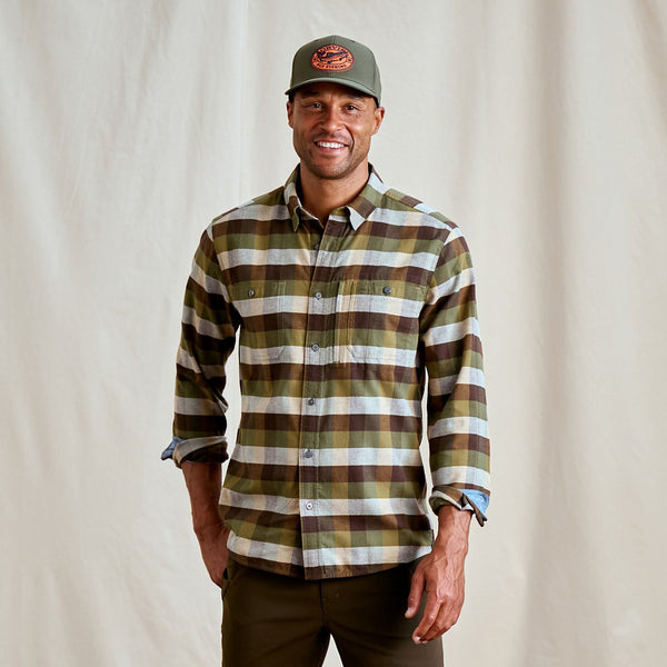 Man wearing a plaid shirt and cap against a plain background