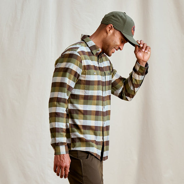 Man wearing a plaid shirt and cap against a plain background