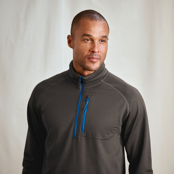 Man wearing a gray pullover with a blue zipper against a plain background