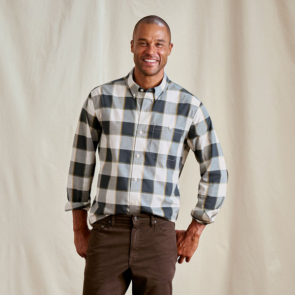 Man wearing a plaid shirt and brown pants against a plain background