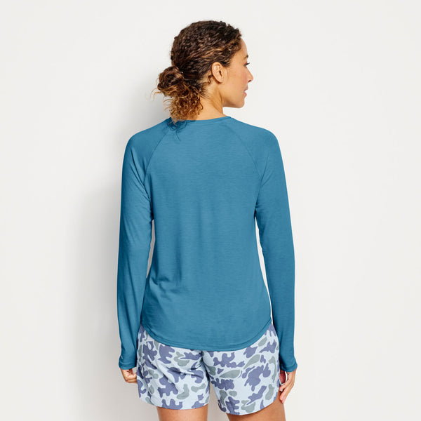 woman facing away from the camera wearing blue sweater and blue camouflage shorts
