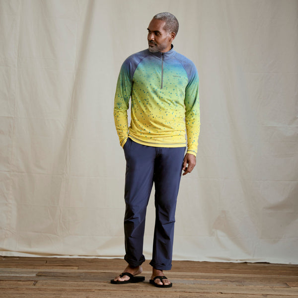man wearing dark blue pants and yellow,green and blue half zipped sweatshirt