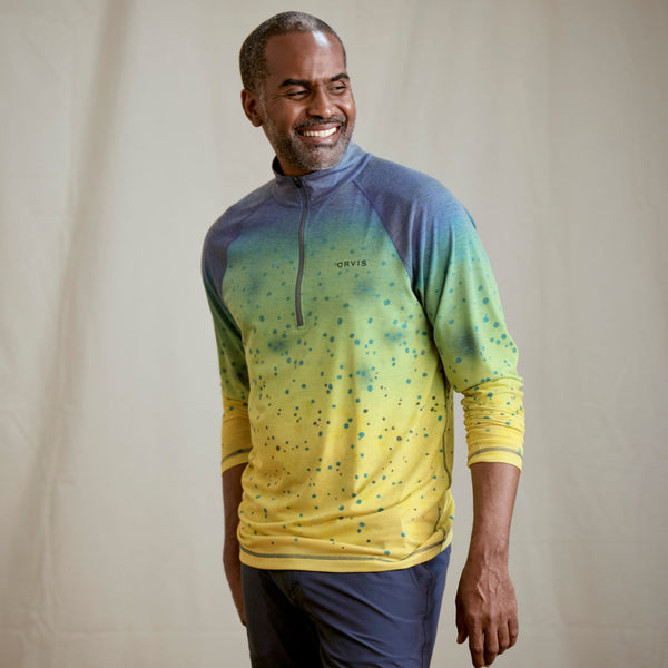 man smiling wearing yellow, gree, and blue half zipped sweatshirt