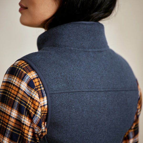 Person wearing a blue vest over a plaid shirt with 'ORVIS' branding.