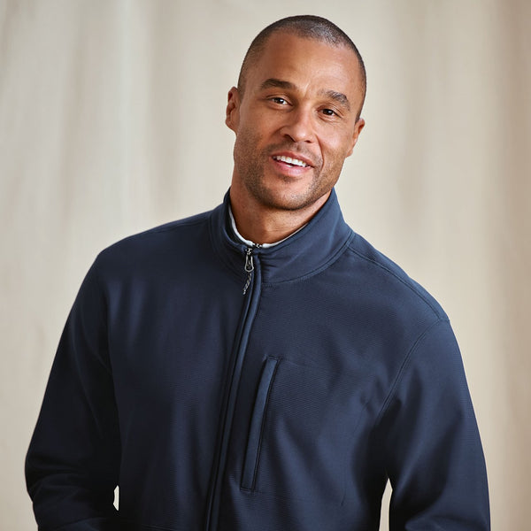 Man wearing a navy blue jacket against a beige background