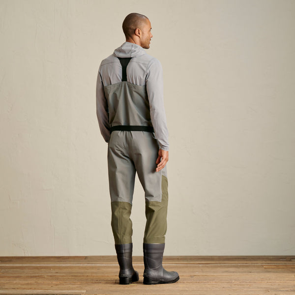 man facing away from camera wearing green and grey waders