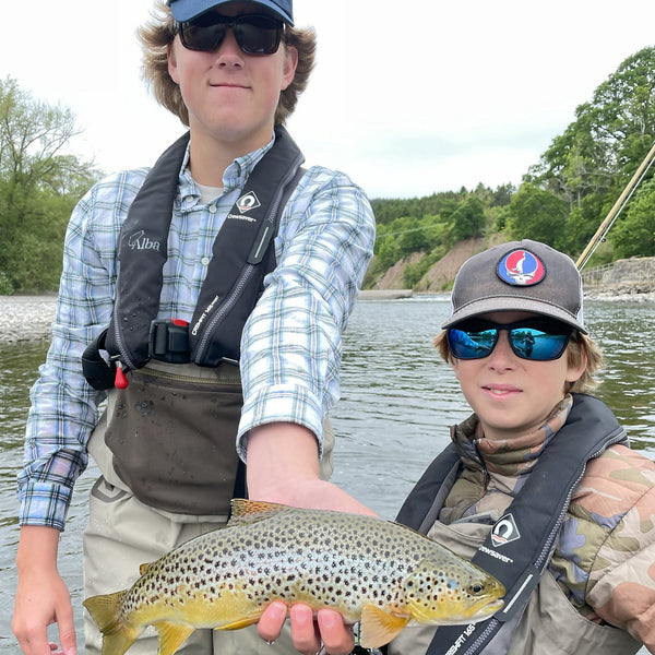 two kids showing trout to the camera