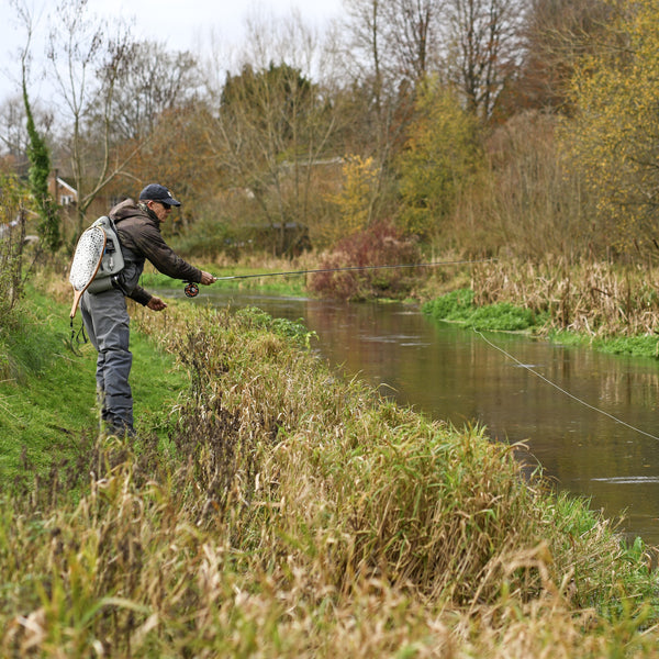 man fly fishing on the side of the river