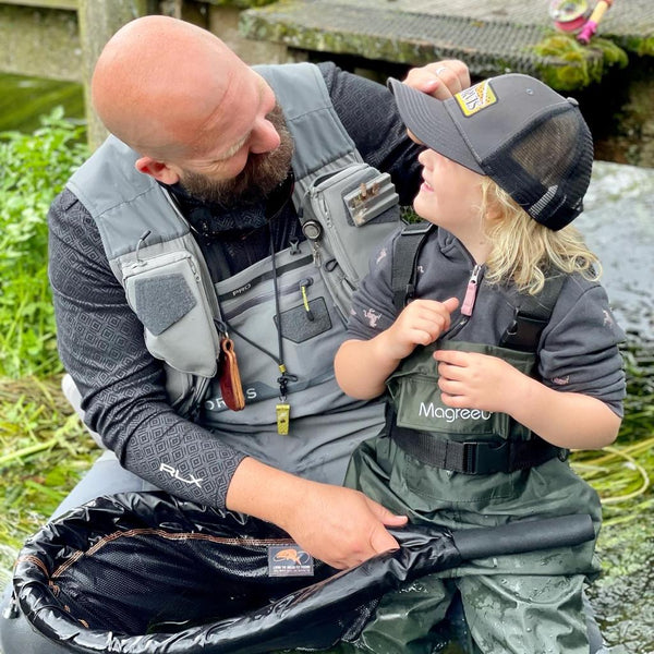 man and child wearing fishing clothes smiling at each other