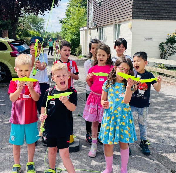 Children holding yellow foam planes in a residential area