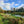 Load image into Gallery viewer, river running through green field with blue skies