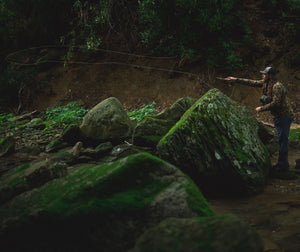 man fly fishing behind rock