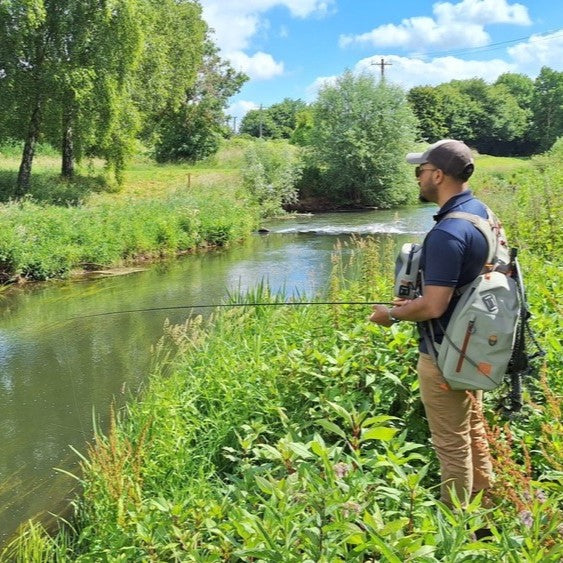 man fly fishing from river bank