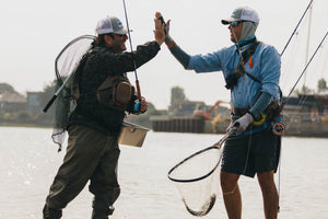 Two male anglers high five each other at the SWFFF