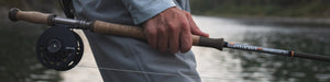 An angler slides a fly rod out of a car-top holder.