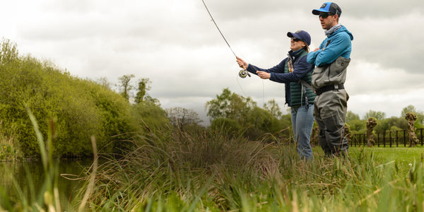 woman fly fishing on riverbank