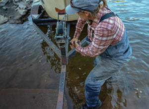An angler wearing Orvis PRO waders cranks their boat out of the river