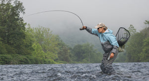 woman wading in river while casting