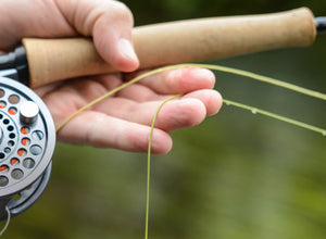 closeup of fly fishing line being held by fisher man