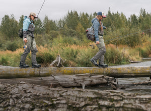two woman walking on three over river