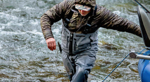 An angler wearing Orvis PRO Zipper waders trudges through rough waters