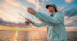 Person fishing on a beach at sunset