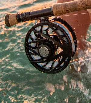 Close-up of a fishing reel with water and boat in the background