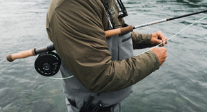 Person fly fishing with a rod and reel on a body of water