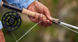 Close-up of a hand holding a Helios fly rod