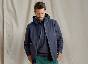 Man wearing a dark blue jacket against a beige background