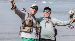 Two anglers raise their fly rods in celebration