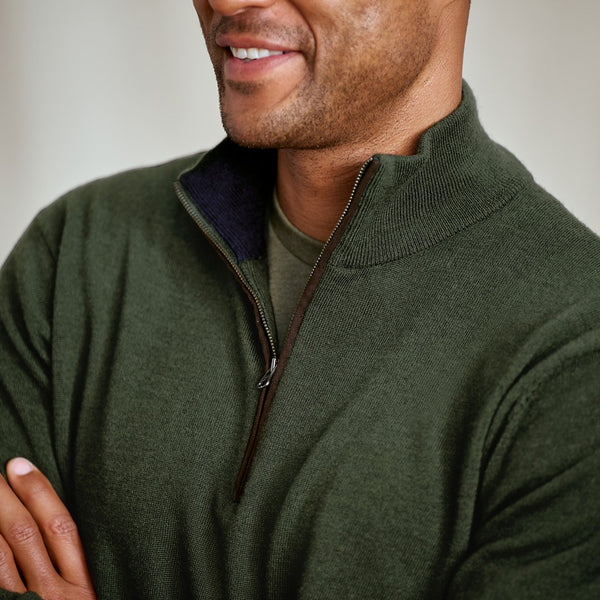 Man wearing a green zip-up sweater with a neutral background