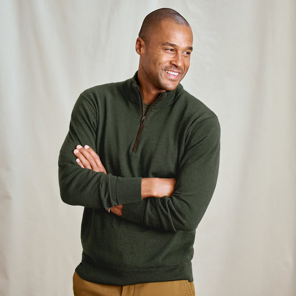 Man wearing a green pullover with a plain background