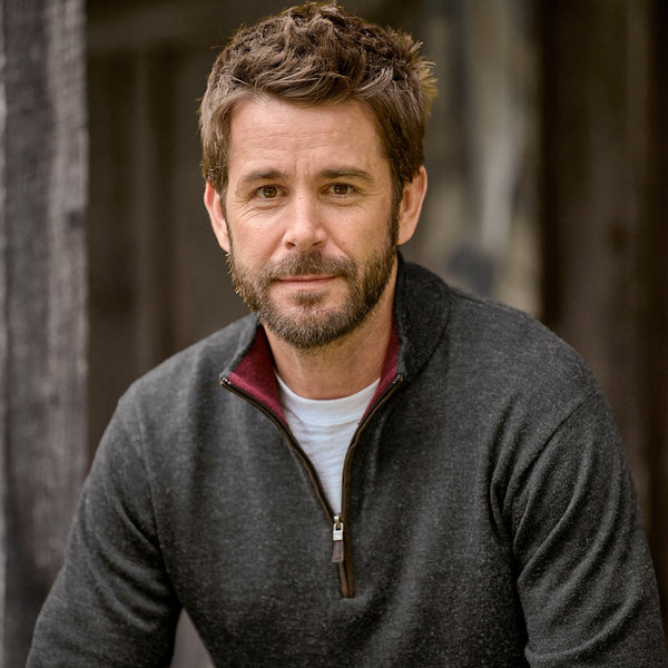 Man wearing a gray zip-up jacket with a blurred background