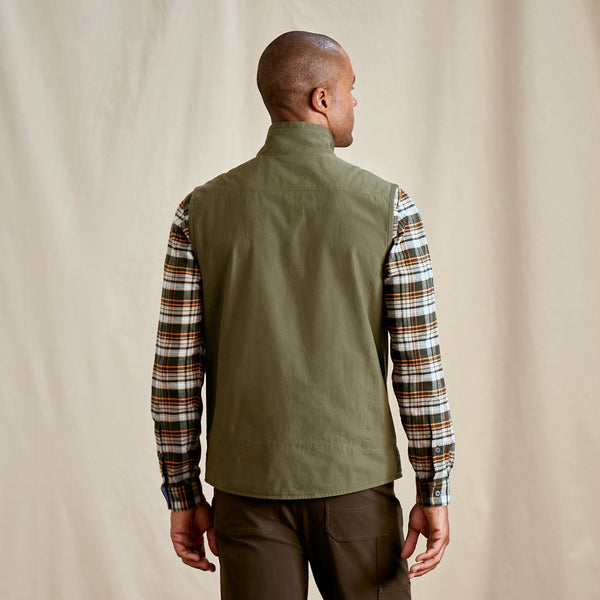 man facing away form the camera wearing checkered shirt and green vest