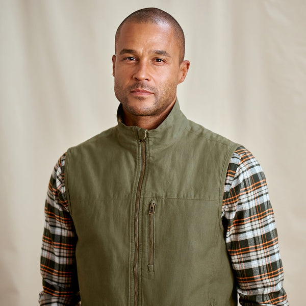 man wearing green vest and brown and orange checkered shirt