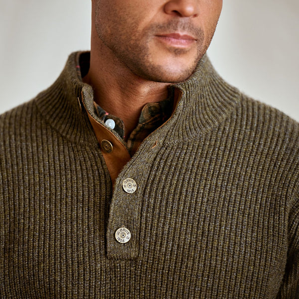 Close-up of a man wearing a brown ribbed sweater with buttons.