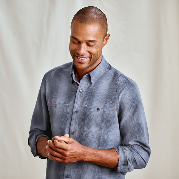 Man wearing a gray checkered shirt against a plain background