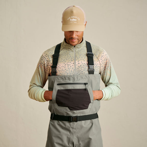 man wearing beige cap, green sweaster and grey waders