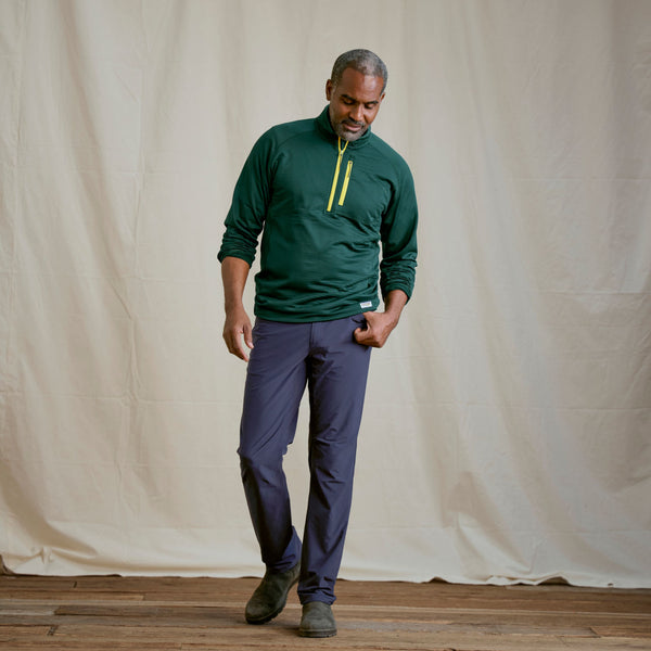 Man modelling blue pants and green half zipped sweather