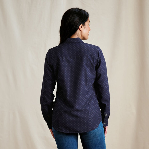 Person wearing a dark blue patterned shirt against a beige background