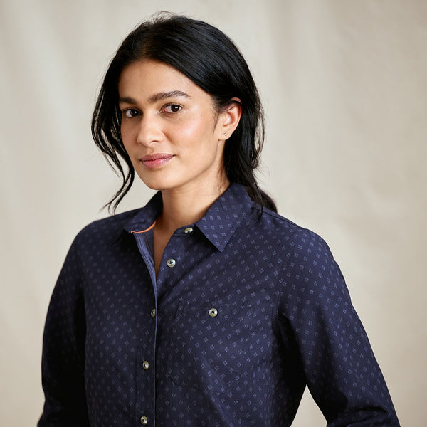 Woman wearing a dark blue patterned shirt against a beige background