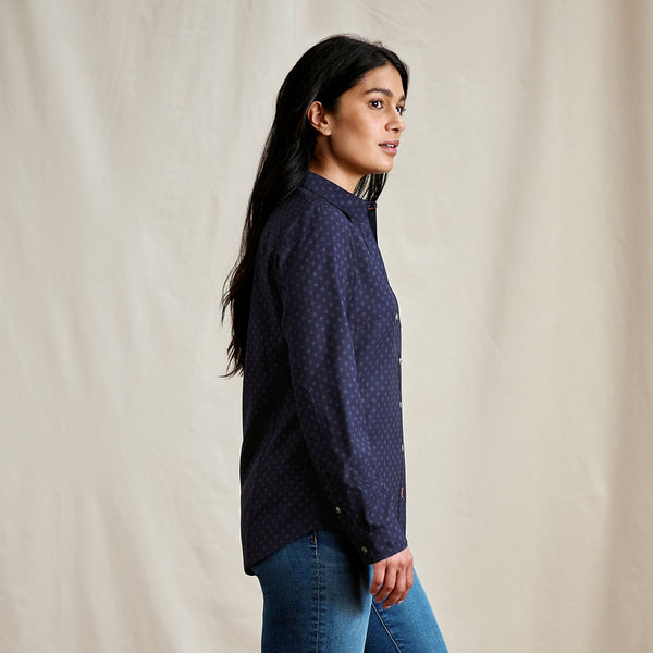 Woman wearing a dark blue patterned shirt against a beige background