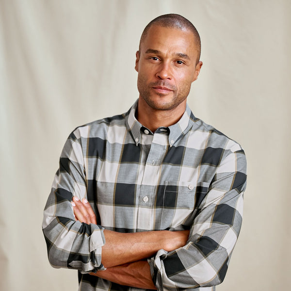 Man wearing a plaid shirt with arms crossed against a plain background